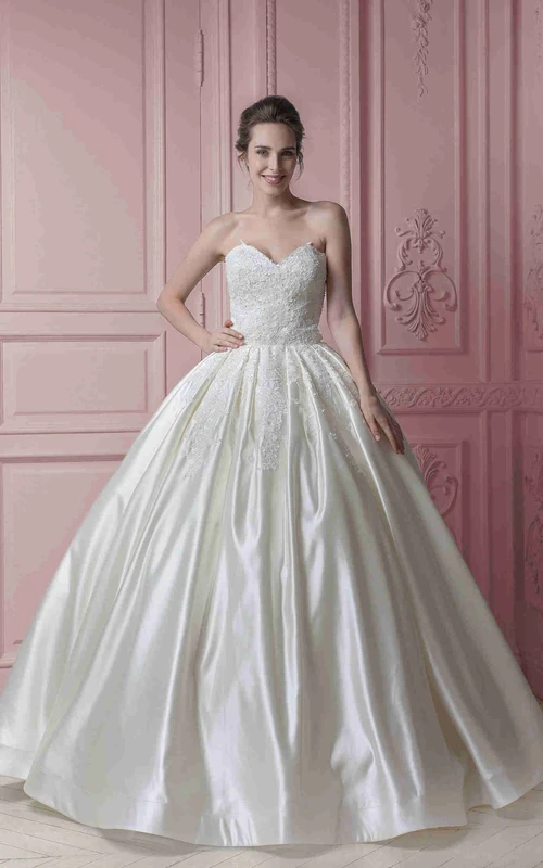 Robe de mariée longue en satin satiné, décolleté cœur, ornée d'appliques et dos corset.
