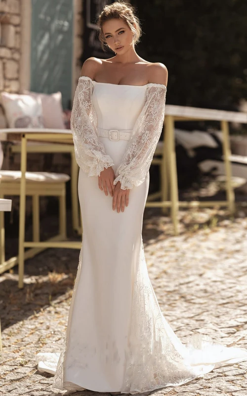 Vestido de novia etéreo de satén con hombros descubiertos, manga larga y fajín con botones.