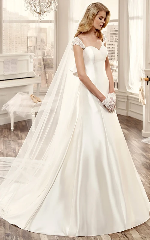 Vestido de novia largo con escote corazón, mangas cortas, gran lazo en la espalda y cola de cepillo.