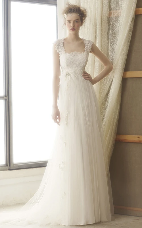 Vestido de novia de encaje y tul de corte imperio, largo hasta el suelo, con cola de cepillo y abertura en forma de ojo de cerradura.