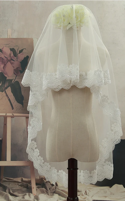 Voile de mariée simple en tulle, bordé de dentelle, arrivant au bout des doigts.