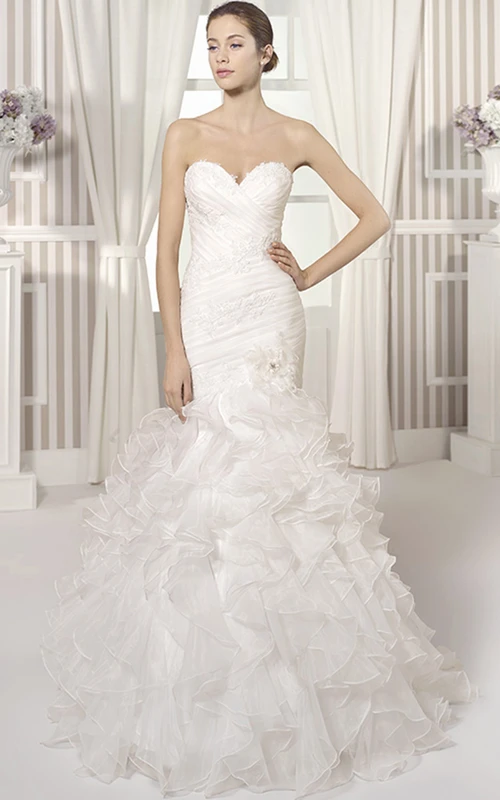 Vestido de novia de organza estilo sirena con escote corazón, tirantes cruzados y volantes.