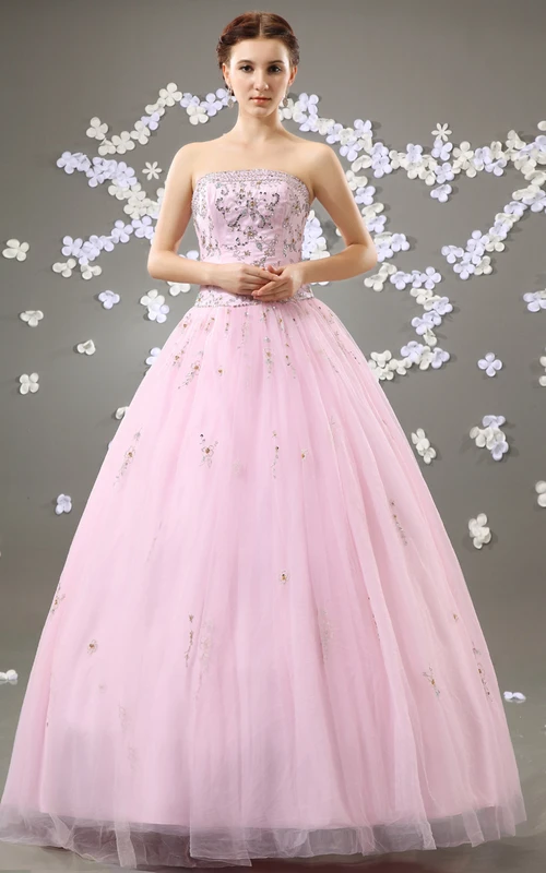 Robe de bal bustier rose poudré, coupe trapèze, ornée de perles et de tulle.