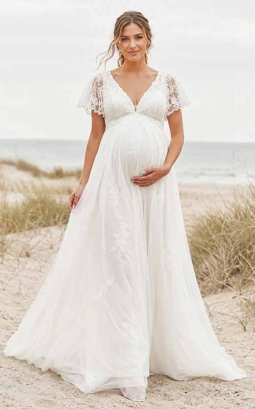Vestido de novia de playa premamá con escote en V, mangas cortas de encaje y falda imperio de tul.