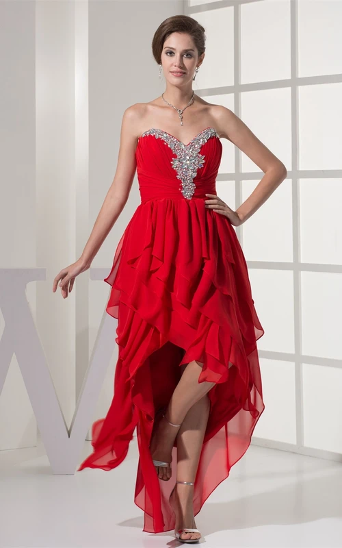 Kleid mit asymmetrischem Saum, Strassbesatz und Rüschen
