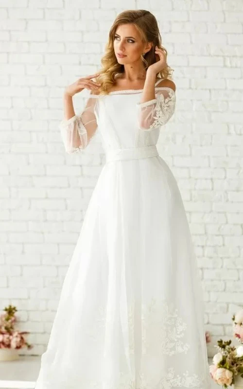 Vestido de novia etéreo de corte A, largo hasta el suelo, de tul, con mangas tres cuartos, cremallera y apliques.