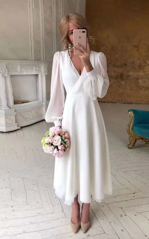 Vestido de novia atemporal de corte imperio con mangas transparentes y escote en V.