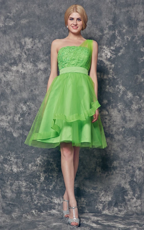 Vestido corto de tul con apliques y volantes en un solo hombro.