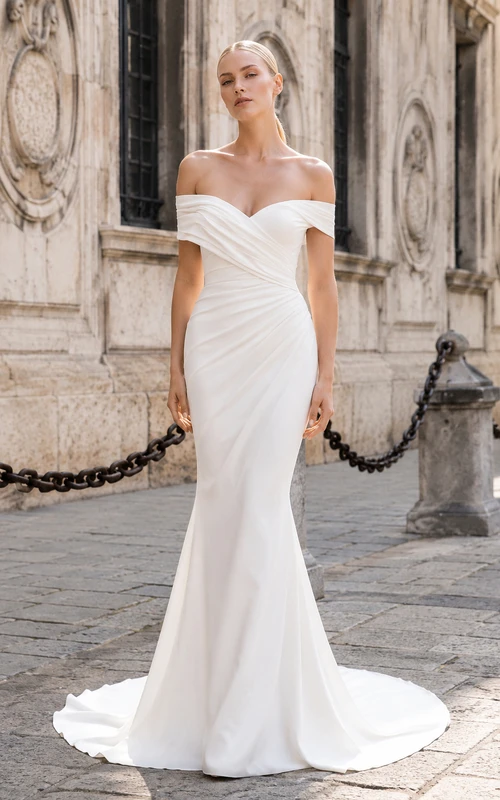 Vestido de novia de satén estilo sirena con hombros descubiertos y corpiño drapeado.