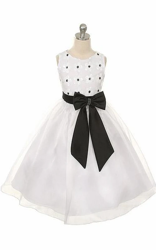 Robe de demoiselle d'honneur mi-longue à volants, ornée de dentelle, de sequins et de nœuds floraux.