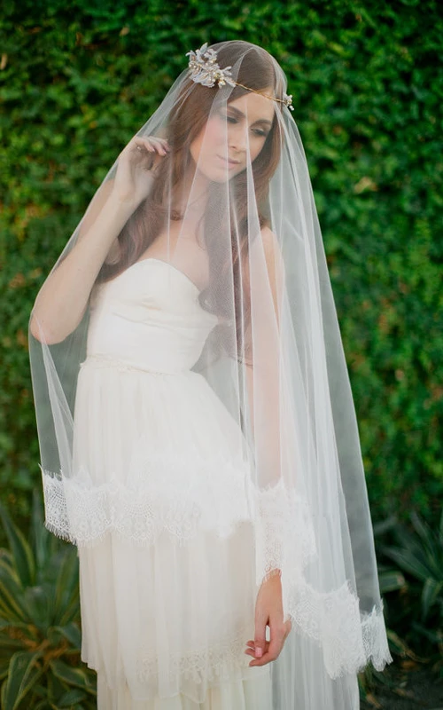 Voile long et souple à traîne orné d'appliqués de dentelle et bordé de dentelle.