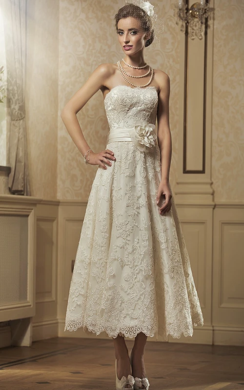 Robe de mariée courte en dentelle sans manches, coupe trapèze, longueur thé, ornée d'appliqués floraux et de bretelles.