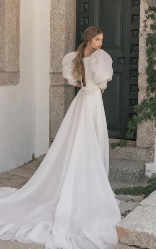 Robe de mariée fourreau en mousseline transparente à manches bouffantes et encolure bateau, avec traîne.