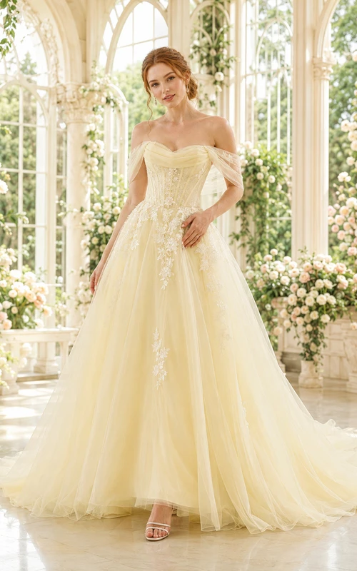 Vestido de novia de corte capilla con tul y encaje color amarillo pálido, hombros descubiertos y cola de capilla.