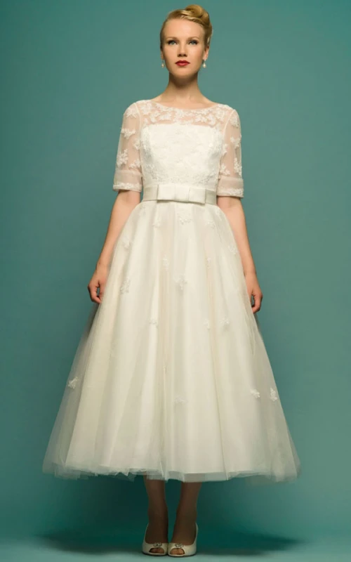 Vestido de novia de corte A, largo hasta la rodilla, escote redondo, manga corta y apliques de tul.