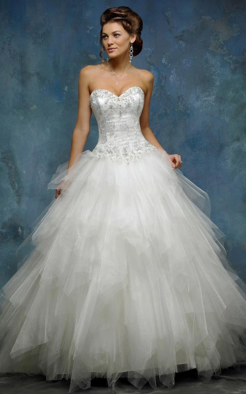Vestido de novia de corte A, largo hasta el suelo, sin mangas, con volantes en cascada, pedrería y cierre de cordones en la espalda.