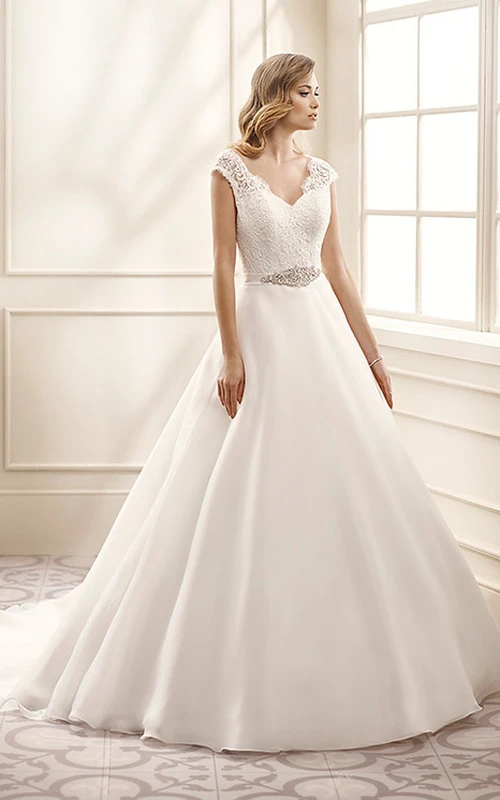 Robe de mariée longue en mousseline et dentelle, coupe trapèze, manches courtes, décolleté en V, ornée de bijoux et d'appliques, dos nu en V
