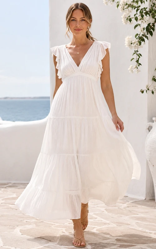 Robe de mariée romantique de destination, décolleté en V, manches papillon, volants, en mousseline à volants, coupe trapèze asymétrique.