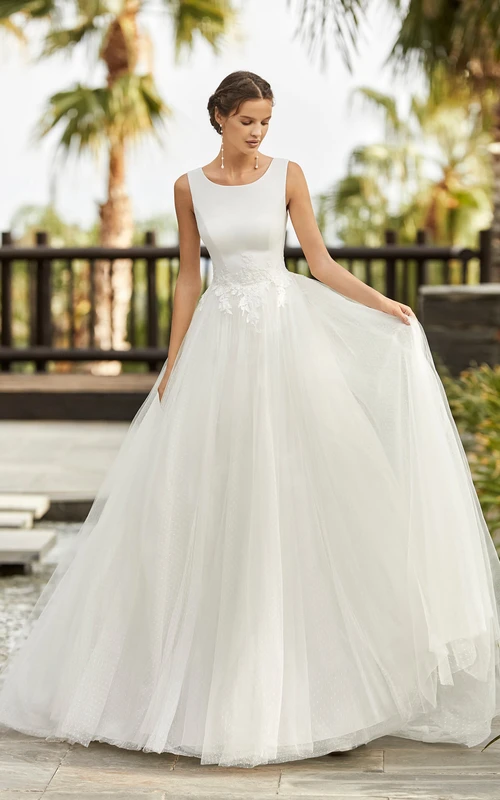 Robe de mariée simple en tulle, ornée de dentelle appliquée, décolleté rond sans manches et dos nu plongeant en V.
