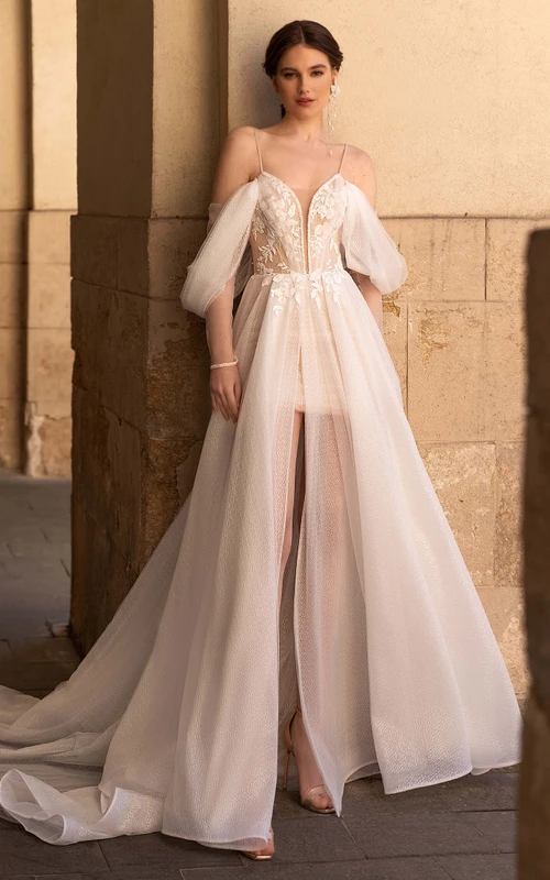 Vestido de novia romántico de corte A, largo hasta el suelo, de tul, manga corta, espalda descubierta y abertura frontal.