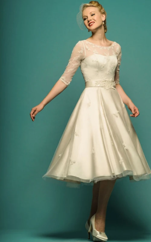 Vestido de novia de corte A, largo hasta la rodilla, con mangas ilusión, escote redondo y apliques de tul.