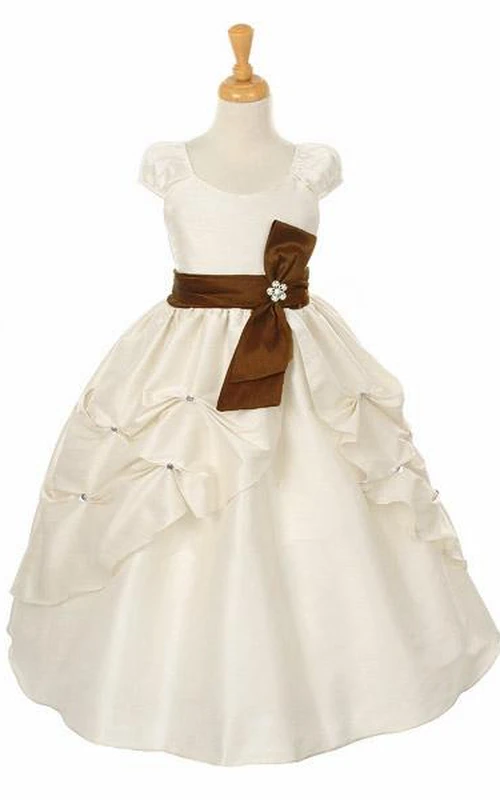 Robe de demoiselle d'honneur longue à volants, ornée de fleurs et d'un nœud, fendue sur le devant.