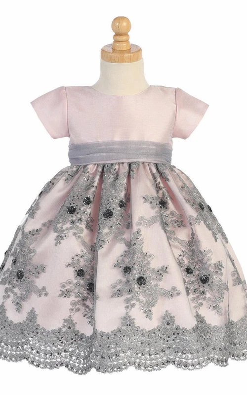 Robe de demoiselle d'honneur mi-longue en tulle brodé de fleurs et de sequins, avec ceinture.