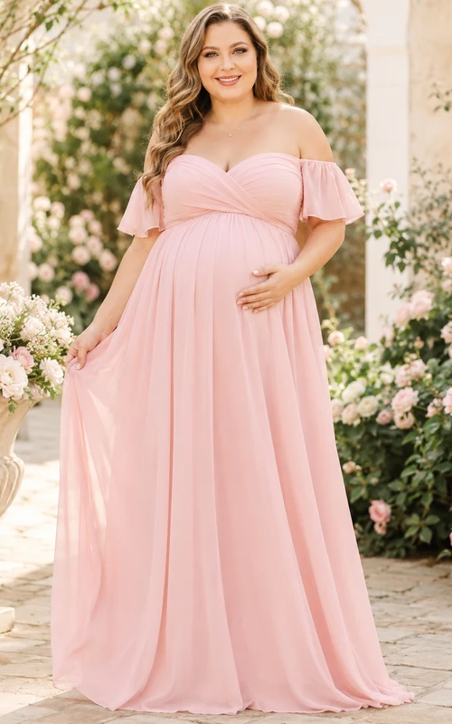 Vestido de maternidad romántico de gasa color rosa empolvado con hombros descubiertos, mangas con volantes y corte imperio, largo hasta el suelo.