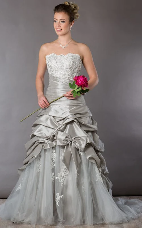 Robe de mariée bustier en tulle ornée d'appliqués, de volants en taffetas et d'un nœud.