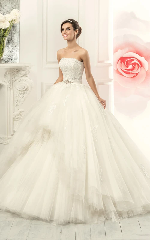 Vestido de gala largo hasta el suelo, sin tirantes, sin mangas, con espalda tipo corsé, de tul, con apliques y joyas en la cintura.
