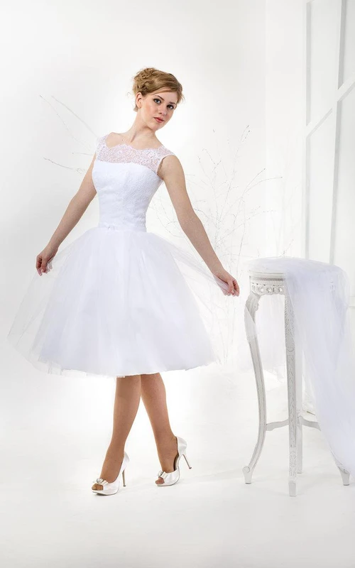 Vestido de tul de manga corta, corte en A, largo hasta la rodilla, con corpiño de encaje.