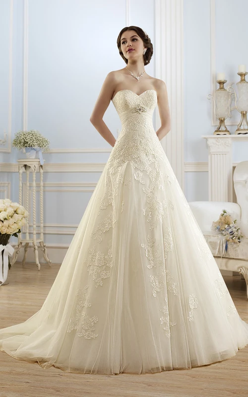 Robe longue trapèze en tulle et dentelle, sans manches, décolleté cœur, lacée, ornée d'appliques et de bijoux de taille.