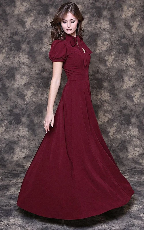 Vestido largo de jersey plisado de corte A con cuello de lazo, mangas abullonadas y abertura en forma de ojo de cerradura.