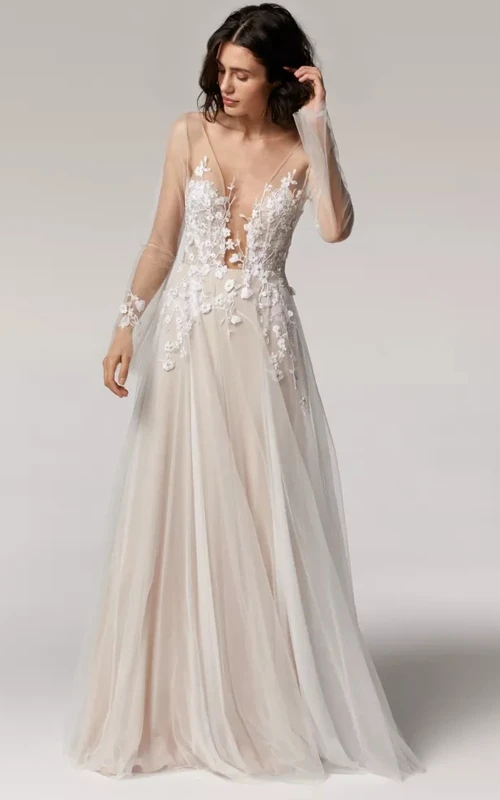 Robe de mariée fluide et vaporeuse en tulle et dentelle appliquée, coupe trapèze illusion, manches longues, ornée d'appliqués.