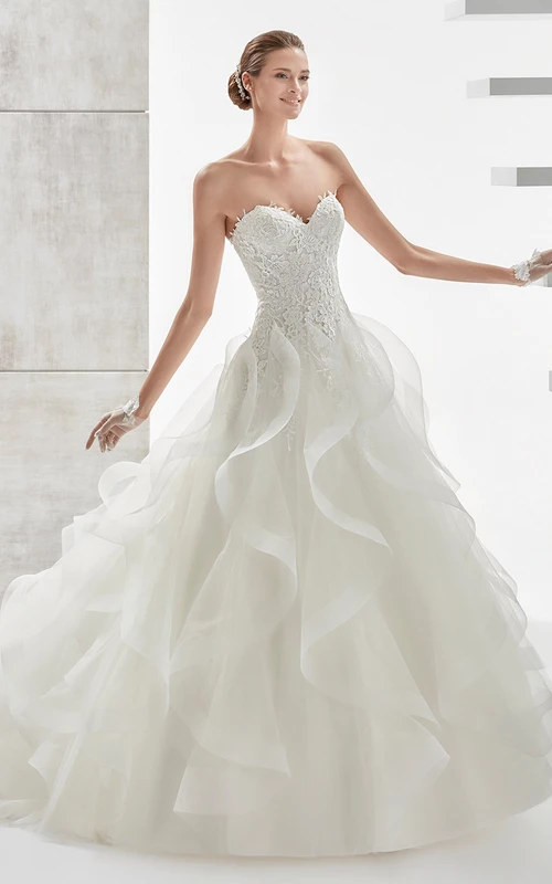 Vestido de corte A con escote corazón, cola corta, corsé de encaje y volantes en cascada.