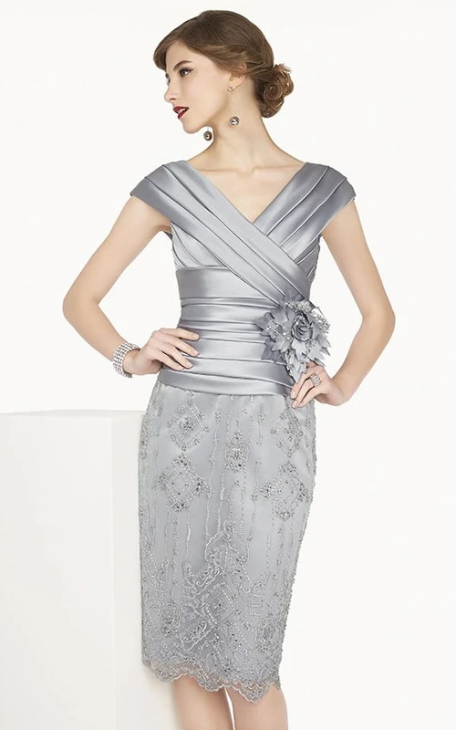 Vestido de encaje satinado hasta la rodilla con escote en V, mangas cortas y detalle de flor (mostrado en color plata).