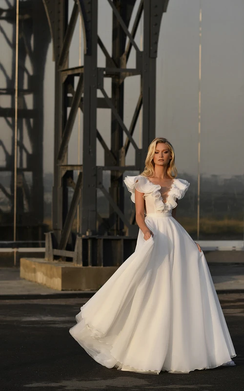 Robe de mariée vintage en mousseline de soie, manches bouffantes, traîne courte, ornée de perles et de volants, coupe bal.