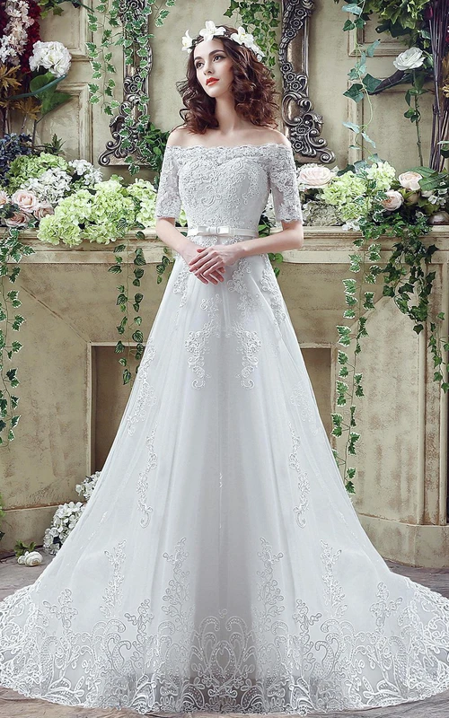 Robe de mariée élégante à épaules dénudées, ornée d'appliqués de dentelle et d'un nœud papillon, avec laçage discret.