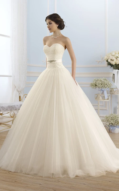 Vestido de gala largo hasta el suelo, escote corazón, sin mangas, sin espalda, de tul, con apliques y joyas en la cintura.
