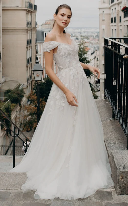 Vestido de novia etéreo de encaje hasta el suelo, manga corta, corte en A, espalda descubierta y apliques.