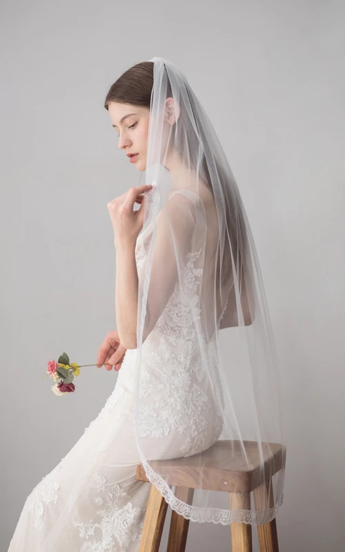 Voile de tulle à un seul niveau, arrivant au bout des doigts, orné de dentelle.