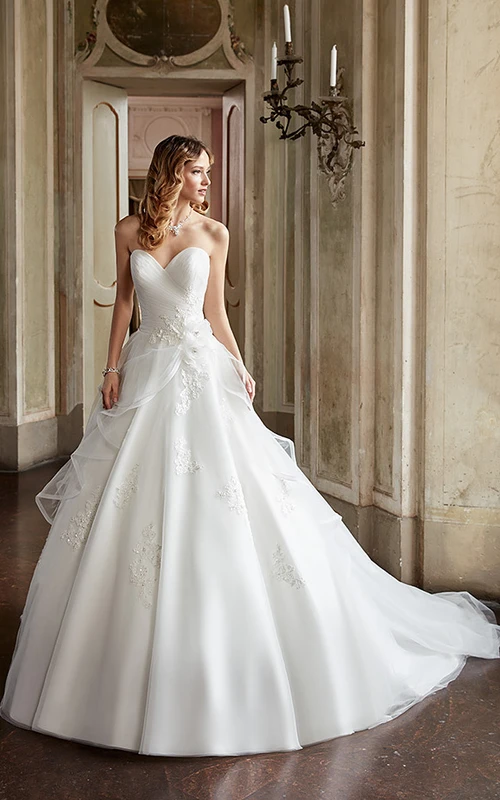 Robe de mariée de bal en tulle à décolleté cœur orné d'appliqués et de fleurs.