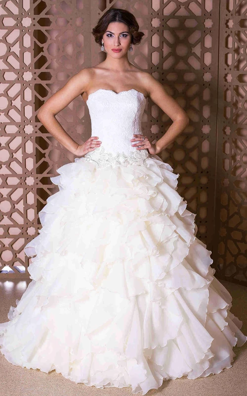 Robe de bal bustier en organza ornée de bijoux, de volants et de dentelle.