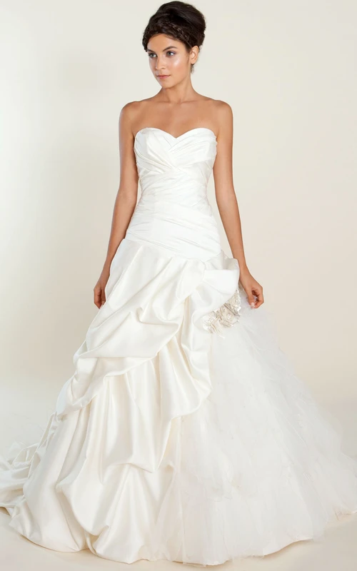 Vestido de novia de gala con escote corazón, recogido en satén y tul, con tiras cruzadas y detalles florales.