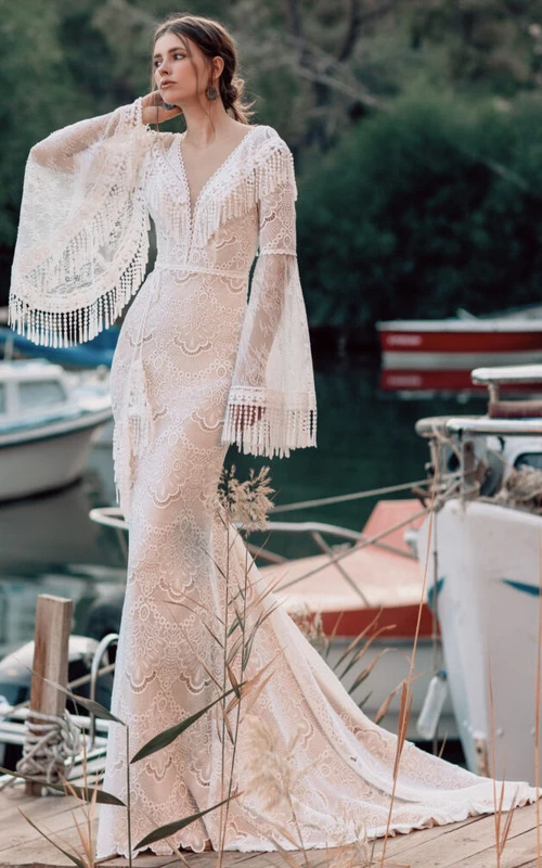 Vestido de novia bohemio de encaje con mangas largas acampanadas y escote pronunciado.