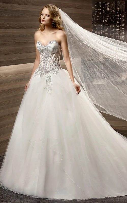 Vestido de novia de corte A con escote corazón, cola de cepillo, corsé con cuentas y falda de tul.