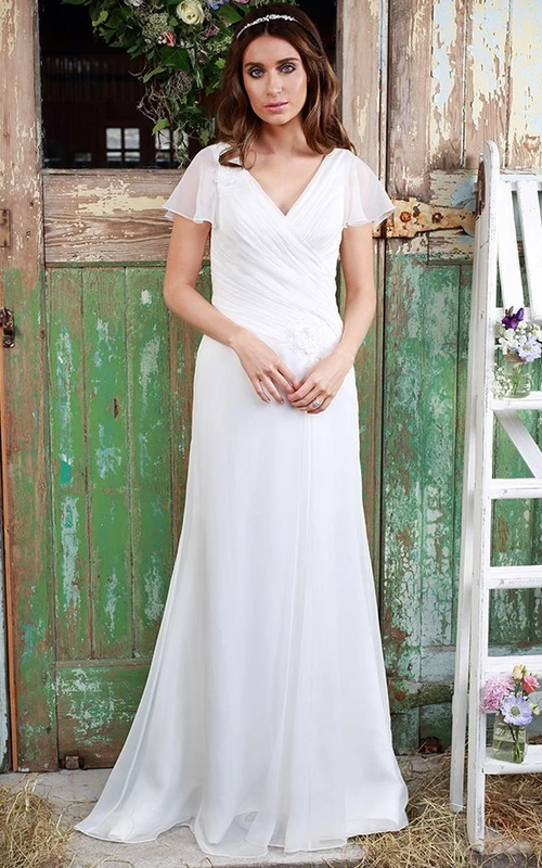 Vestido de novia de gasa con escote en V, mangas estilo poeta y detalle cruzado.