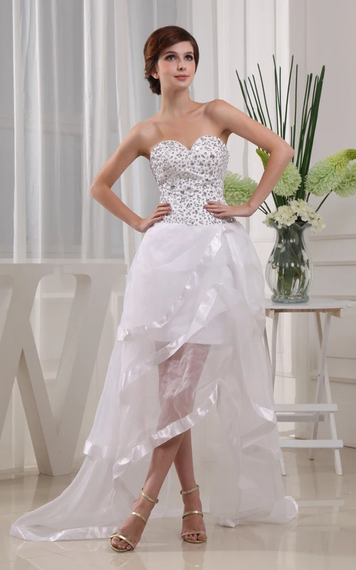 Elegante vestido asimétrico con escote corazón, bordados y volantes.