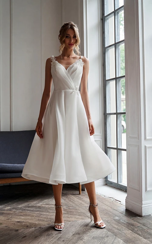 Robe de mariée empire en mousseline spaghetti, coupe trapèze croisée, ornée d'appliqués. Décolleté croisé. Appliques.