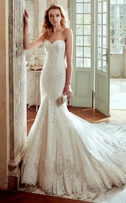 Vestido de novia estilo sirena con escote corazón, apliques de encaje y cola de corte.